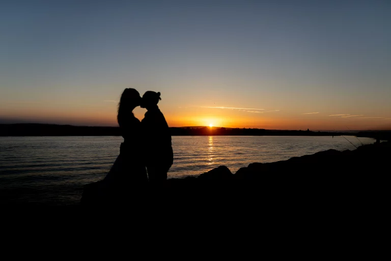 Photo en silhouette de deux futurs mariés qui s'embrasse aux soleils couchants. photographier par un photographe de mariage