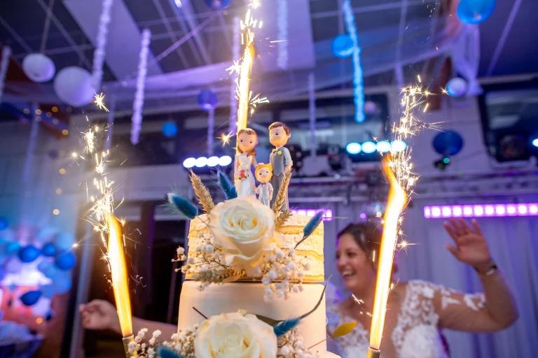 Photographe de mariage, photo du gâteau lors d'un mariage, avec les bougies fontaines en fond et les statuettes des deux mariées en premier plan