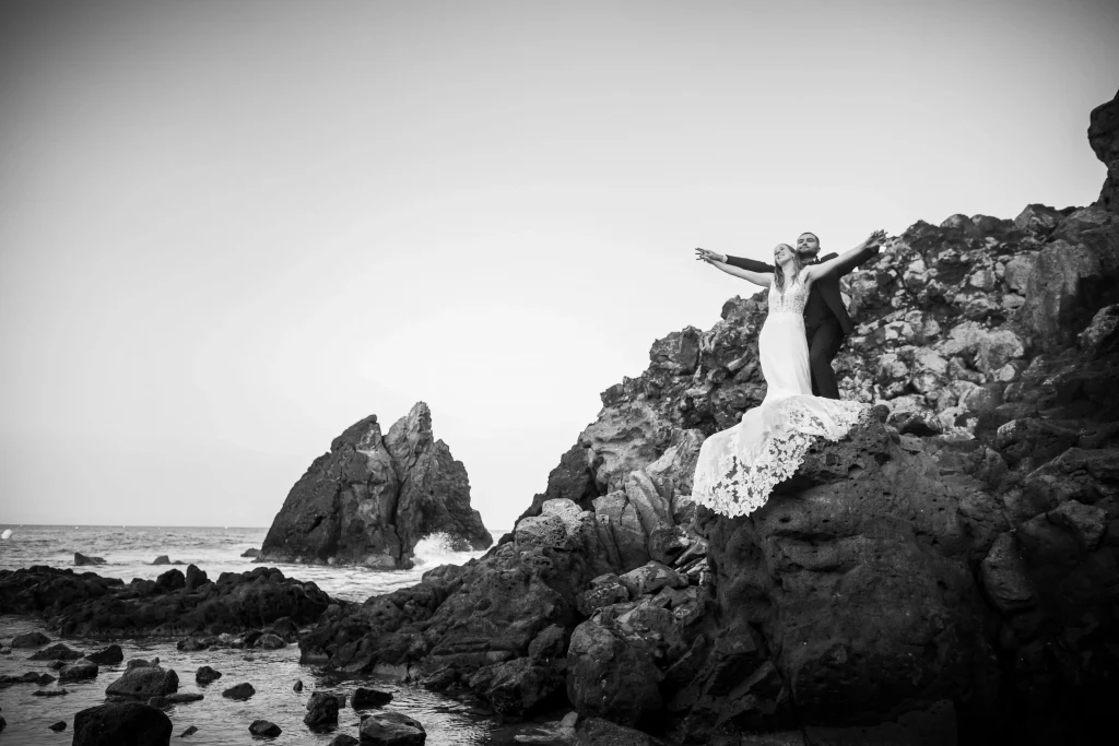 Séance day after après le mariage, au cap d'agde à la plage de la grande conque les mariées sont sur un rocher et lève les bras comme dans le film titanic avec en premier plan les rochers