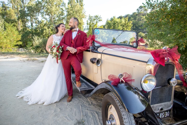 séance de couple, le marié est appuyé sur une voiture ancienne et la mariée le regarde avec tendresse