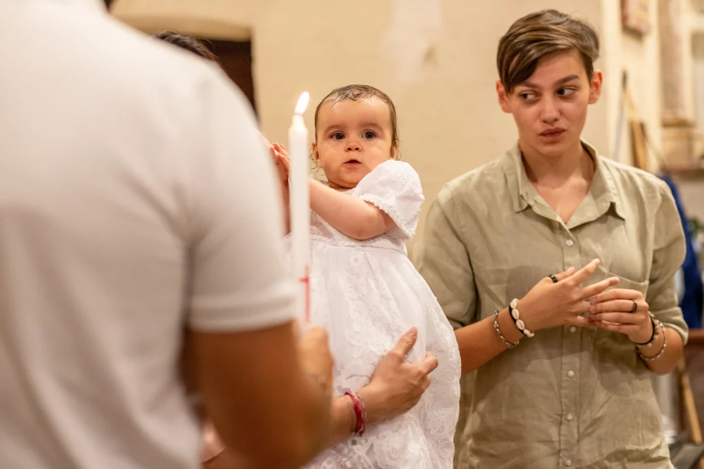 Petite fille lors d'un baptême qui regarde la bougie après avoir été béni