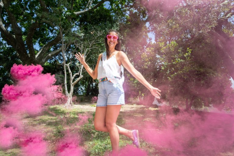 future mariée qui s'amuse avec des fumigènes roses dans un parc durant son EVJF