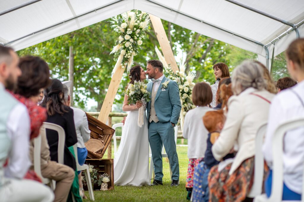 Mariage de Coralie et Fred dans l'Hérault, je suis au centre de l'allée et je shoot les mariées qui s'embrasse devant l'hôtel lors de leurs cérémonie laïque