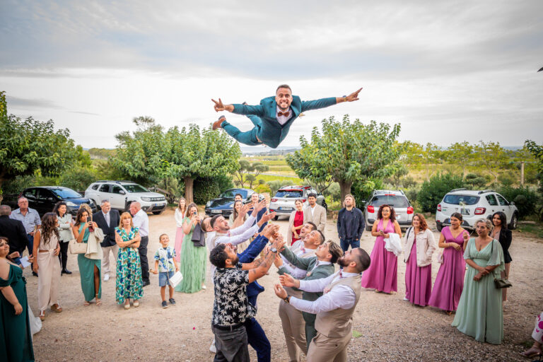 photographie de mariage de Carlen et Davidson, le marié est envoyé en l'air par ses témoins durant les photos de groupe