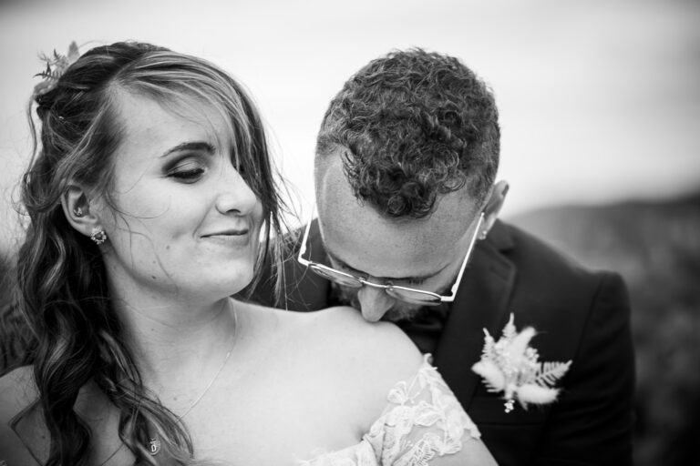 Mariage de Carlen et Davidson à Béziers, le marié embrasse tendrement la mariée sur l'épaule, photographie en noir et blanc