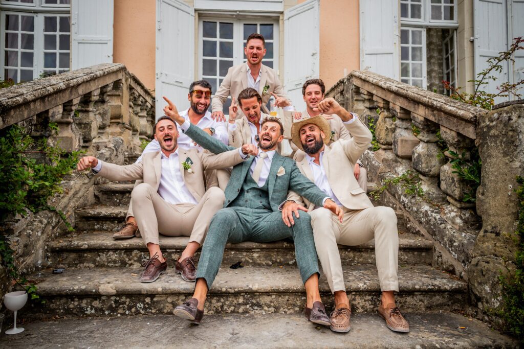 mariage de Eleonore et Louis, le marié est assis dans un escalier avec tout ses témoins, et ils crient tous, photographe de mariage dans le GARD