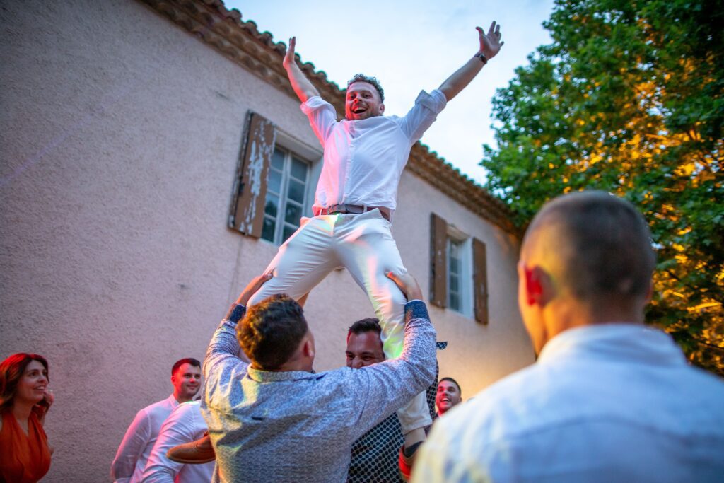 mariage de Maxime et Muge, un invitée est porté et lève les bras durant le mariage à Alès