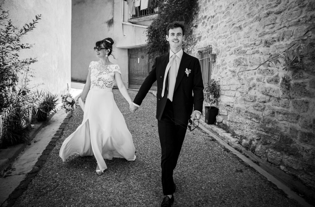 photographie de mariage de Mélanie et Alban, les mariées se promène dans la rue mains dans la mains, photographie en noir et blanc dans le gard