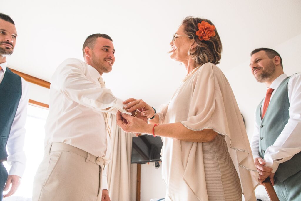 photographie de mariage de Priscila et Steven, la maman du mariée lui arrange les boutons avant la grande cérémonie