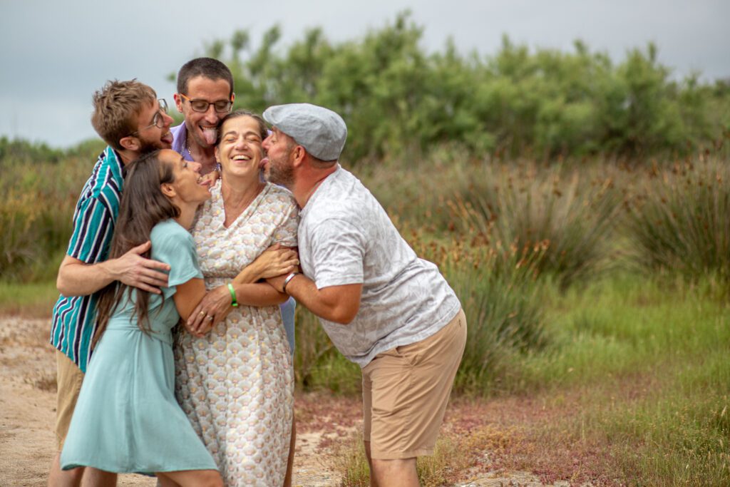 photographie de famille à Montpellier, les enfants embrasse la maman et profite pour lui faire des léchouille. photo en couleur prise en extérieur prés de la plage