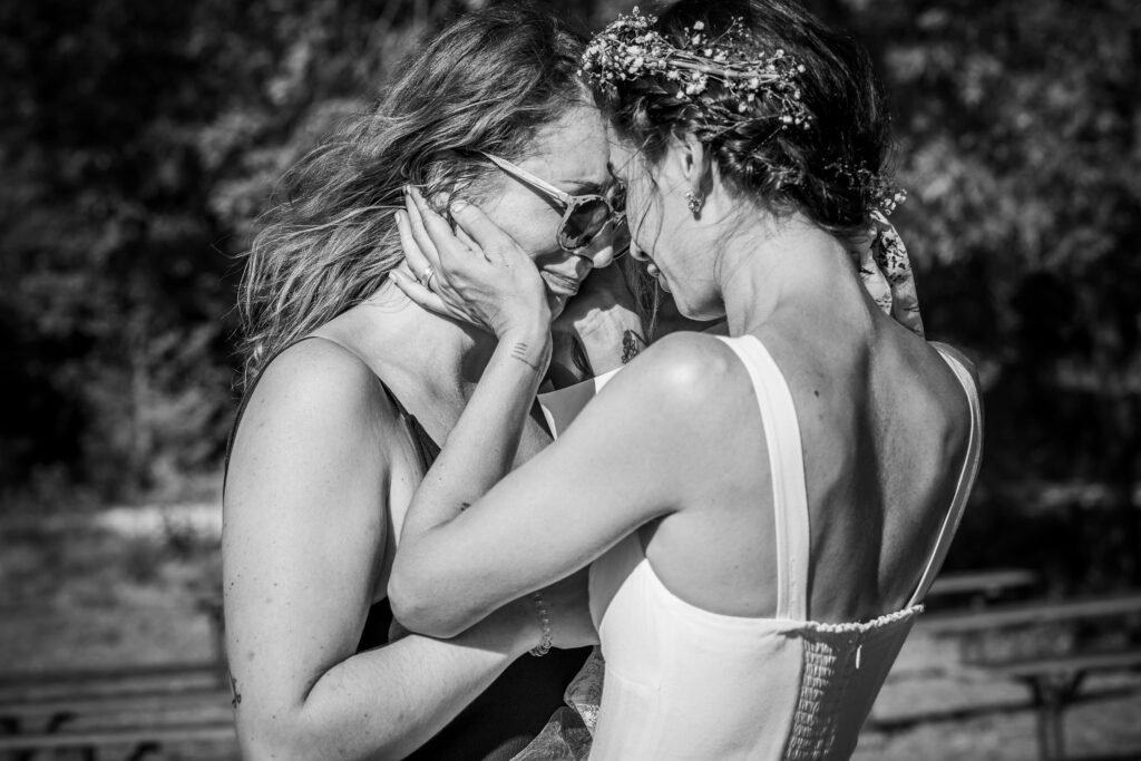 Une sœur rassure la mariée en lui tenant délicatement le visage pendant les préparatifs du mariage.