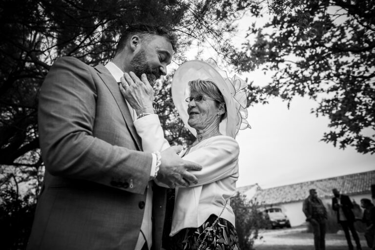 La mère du marié caresse tendrement le visage de son fils pendant les préparatifs du mariage.